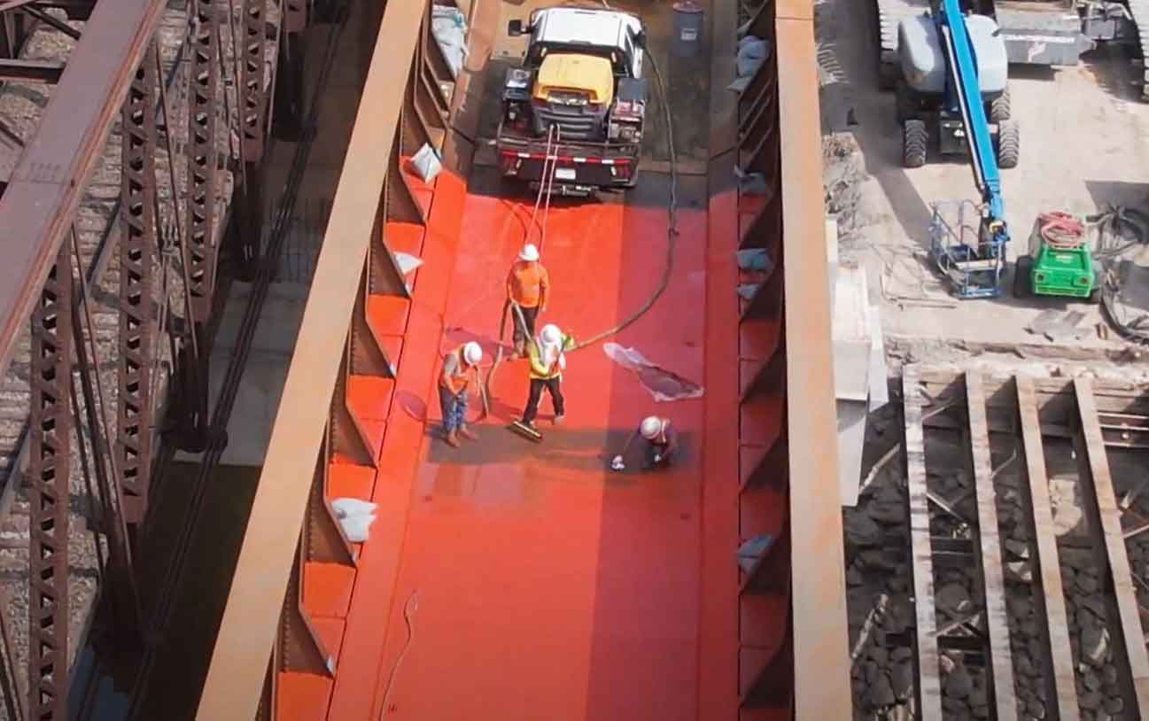 ASFI Construction crew applying waterproofing membrane to highway bridge deck using specialized spray equipment