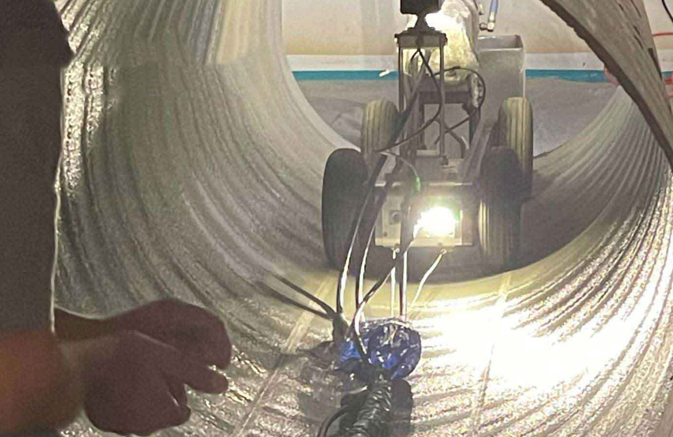 Spray In Place Pipe (SIPP) operation showing technicians applying polyurea coating inside large concrete culvert